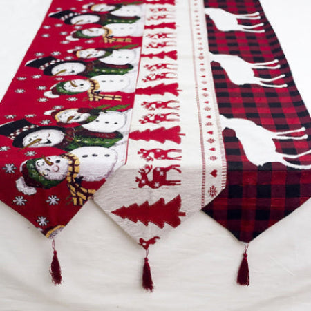 Kerst tafelloper 35×180 cm – close-up van rendier- en sneeuwpopprint met kwastjes, bovenaanzicht op tafel.