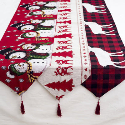 Kerst tafelloper 35×180 cm – close-up van rendier- en sneeuwpopprint met kwastjes, bovenaanzicht op tafel.